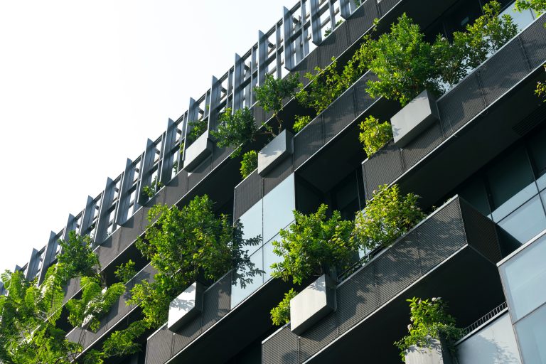 Eco-friendly building in modern city. Sustainable glass office building with trees for reducing CO2.